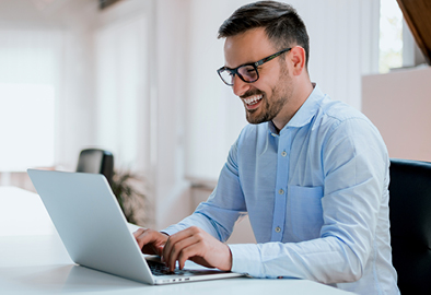 Foto de homem sorrindo em frente do computador